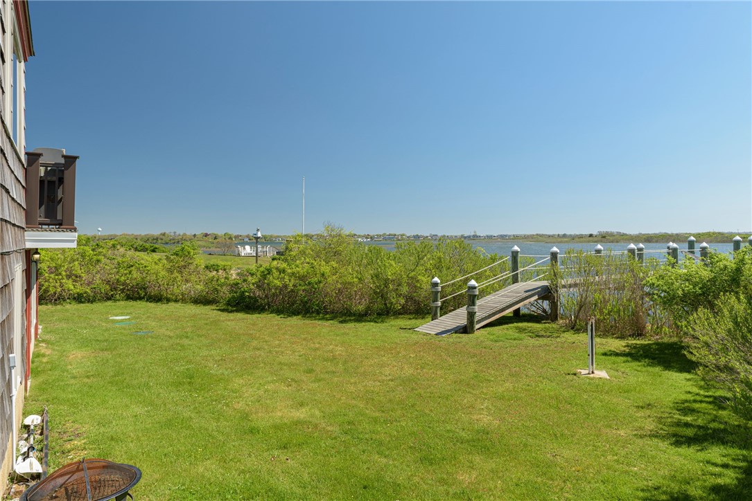 Waterfront yard with a broad lawn and a wooden ramp leading to a dock.