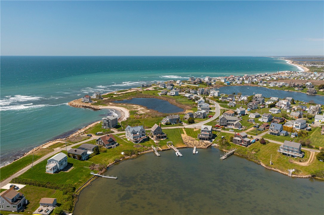 Aerial view of coastal homes around an inlet, with docks and ocean shoreline.