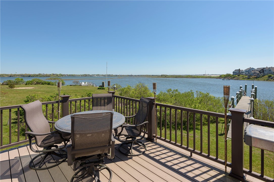 Waterfront deck with patio dining set, dock, and broad inlet view.