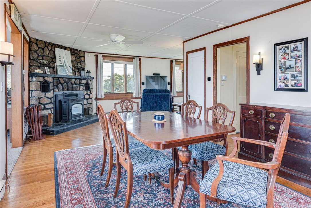 Dining room with a wooden table, patterned chairs, and a stone fireplace with a wood stove.
