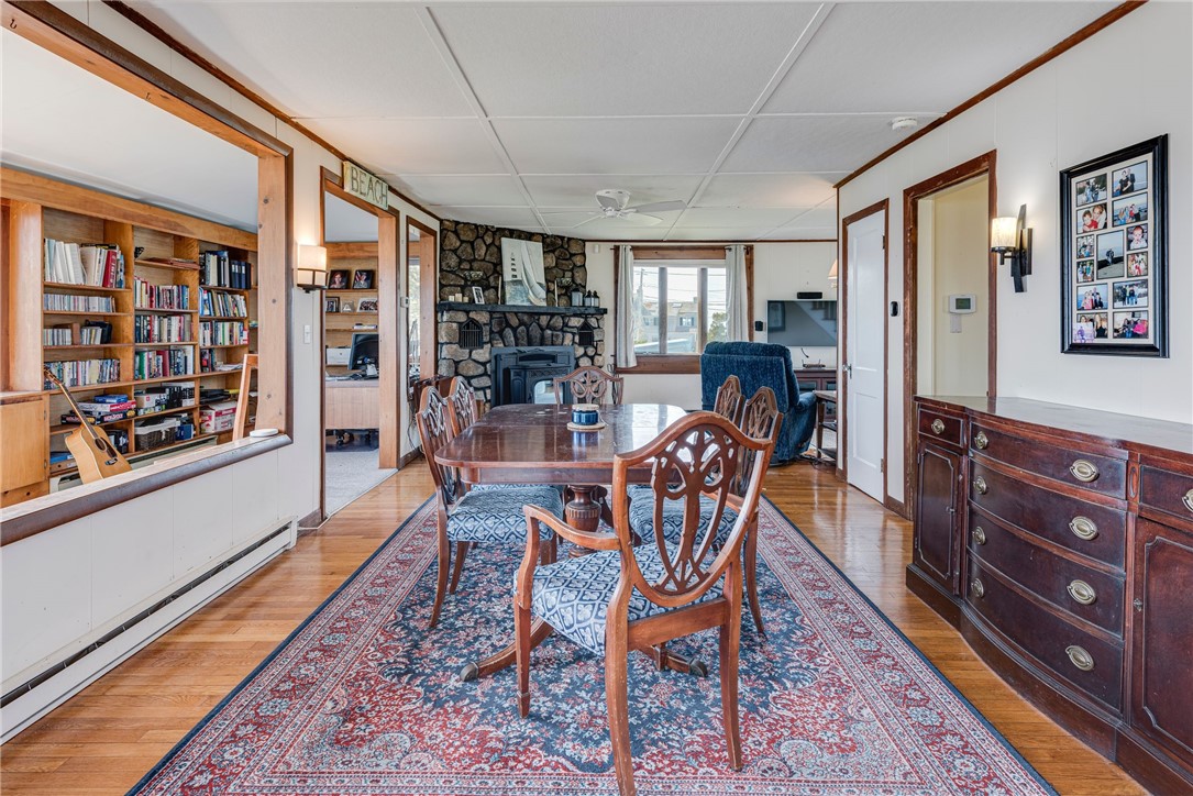 Dining room with a stone fireplace, patterned rug, and built-in bookshelf visible through an opening.