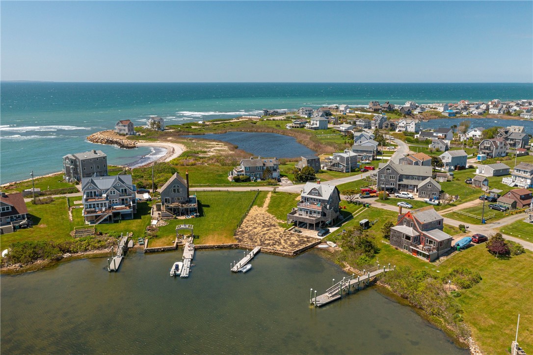 Coastal homes and private docks along an inlet, with a beach and ocean beyond.