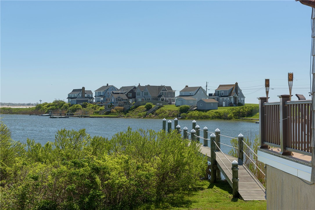 Waterfront view with a wooden dock, shoreline homes, and a deck overlooking the channel.