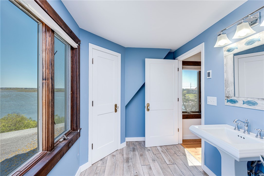 Blue bathroom with a white sink and a window overlooking the water.