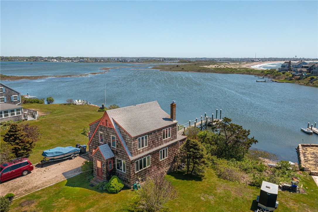 Waterfront shingle house beside an inlet, with a private dock and broad green lawn.