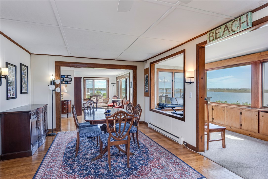 Dining room with a patterned rug, wood trim, and windows overlooking the water.