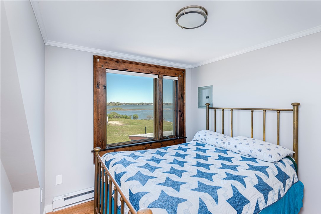 Bedroom with a brass bed and a large window overlooking the water.