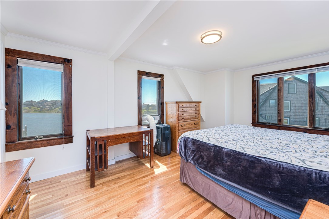 Bedroom with hardwood floors, dark wood trim, and a window overlooking the water.