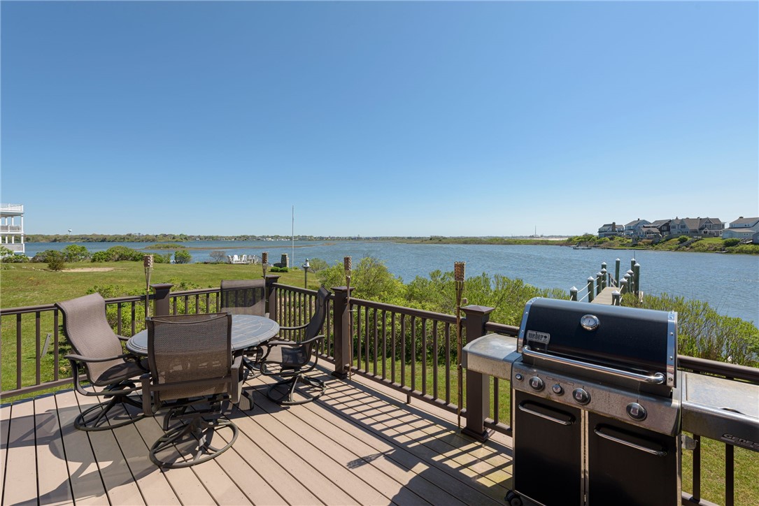 Waterfront deck with patio dining set and gas grill overlooking the water