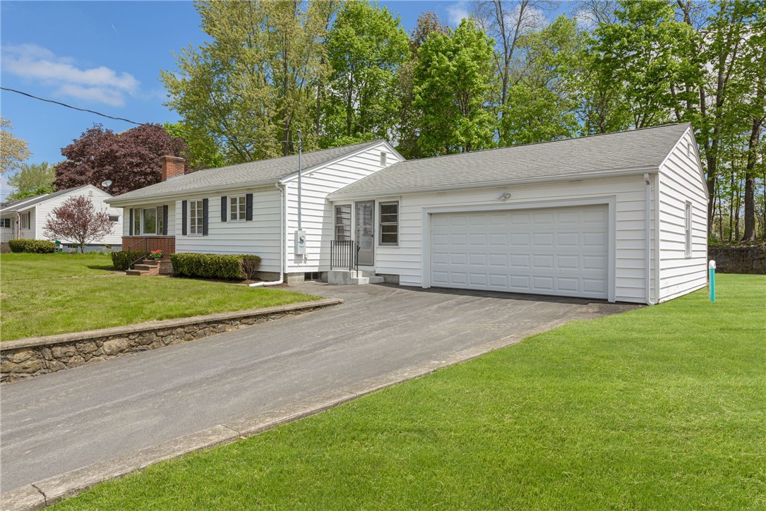White ranch house with an attached two-car garage and broad paved driveway.