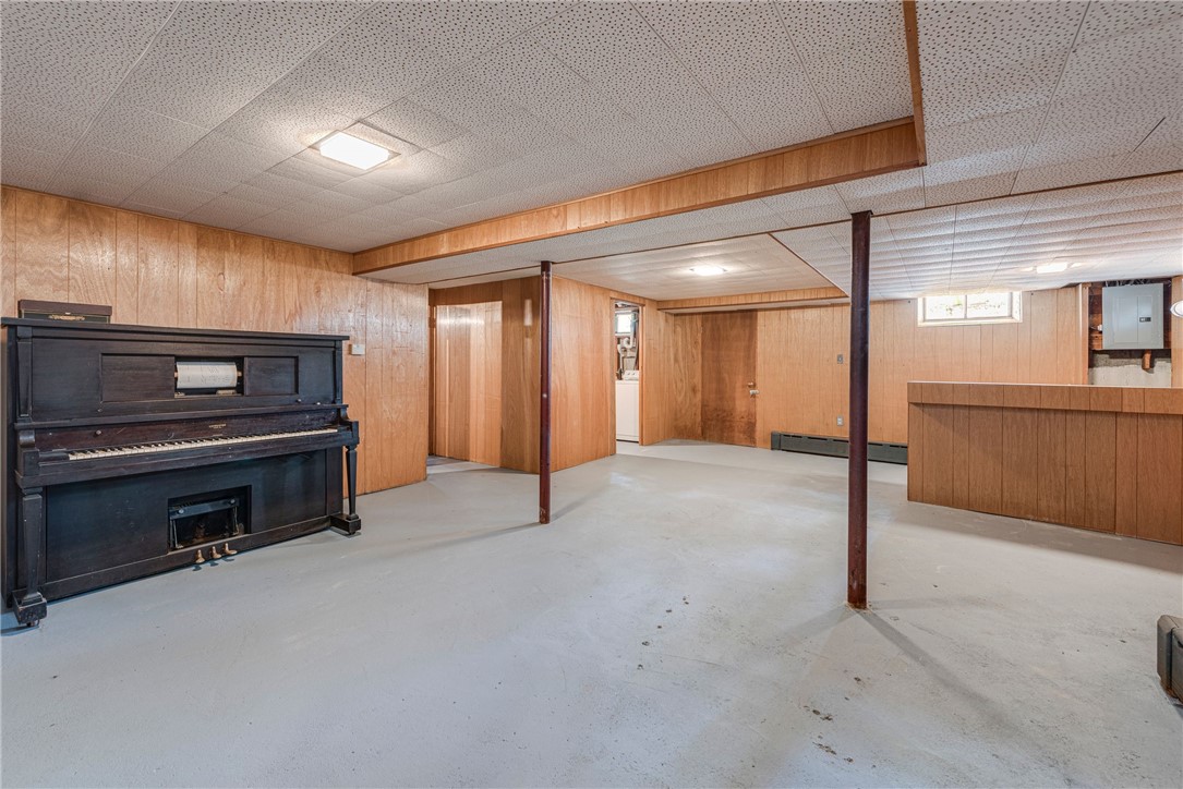 Basement with wood paneling, concrete floor, built-in bar, and upright piano.