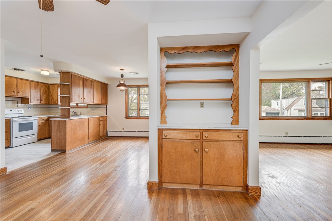 Kitchen and adjoining dining area with wood cabinets, hardwood floors, and a built-in shelving nook.