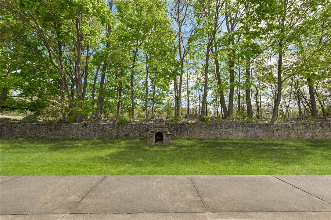 Green lawn and mature trees behind a stone wall with a small arched opening.