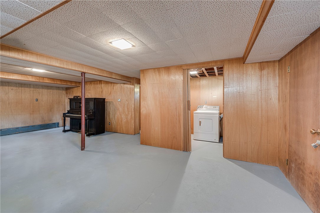 Wood-paneled basement with an upright piano and a dryer in a separate laundry area.