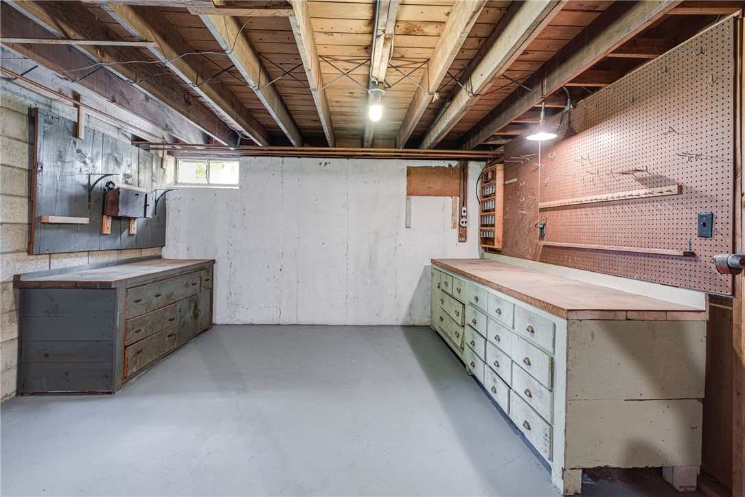 Basement workshop with built-in drawer workbenches and pegboard walls.