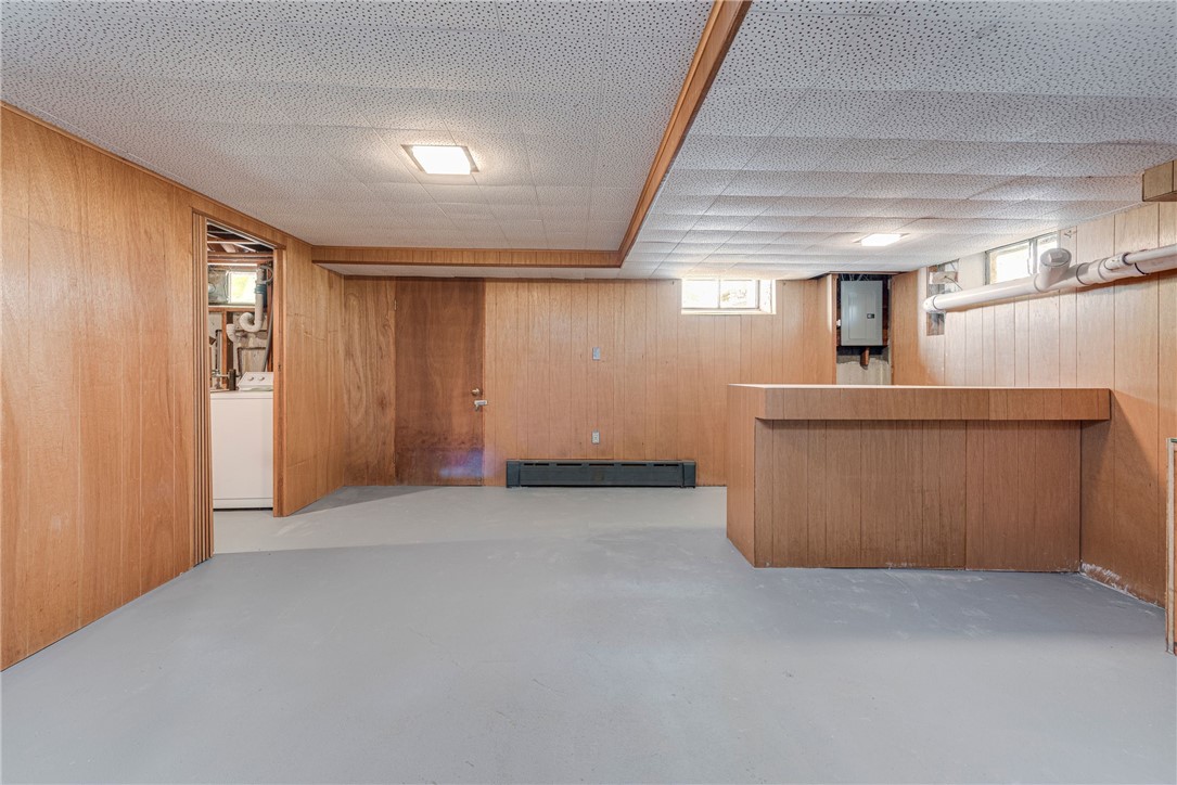 Vacant wood-paneled basement with a built-in bar counter and an open utility-room doorway.