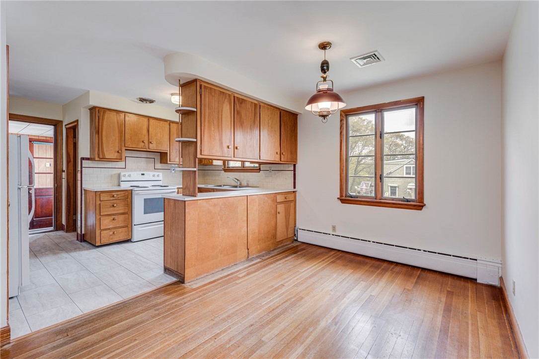 Kitchen and dining area with wood cabinetry, white appliances, and hardwood floors.