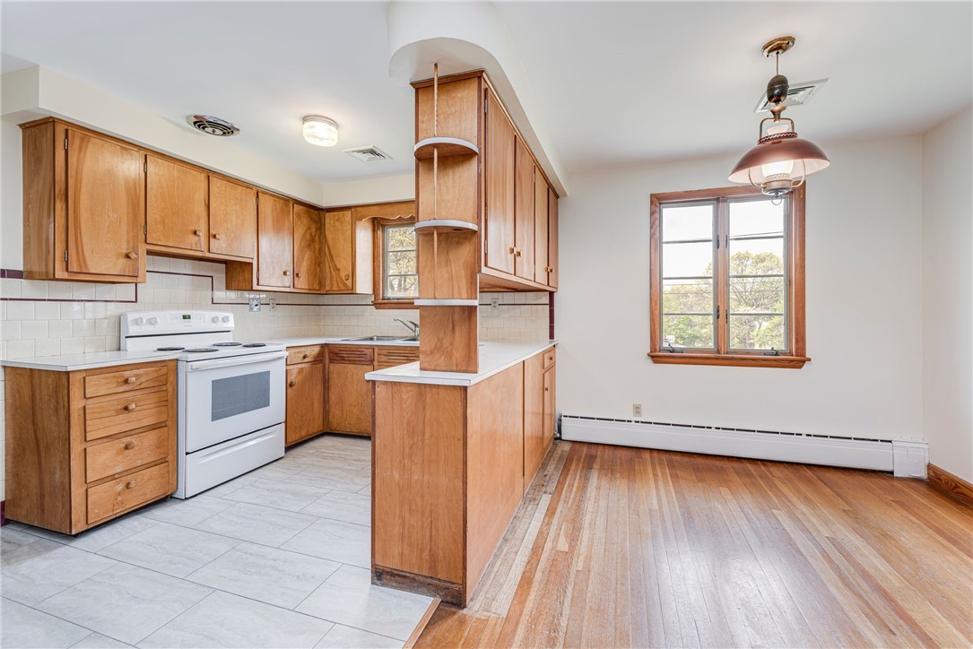 Kitchen and dining area with wood cabinetry, tiled kitchen floor, and hardwood dining floor.