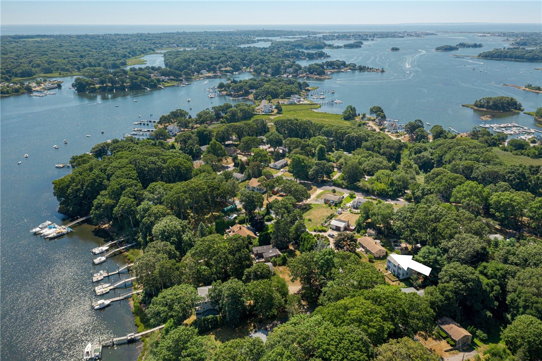 Aerial view of a wooded waterfront neighborhood, with a white marker highlighting a house near the bay.