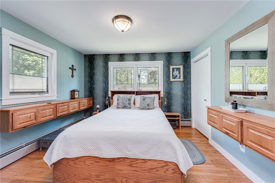 Bedroom with a white quilted bed, floral accent wall, and built-in wood cabinetry.