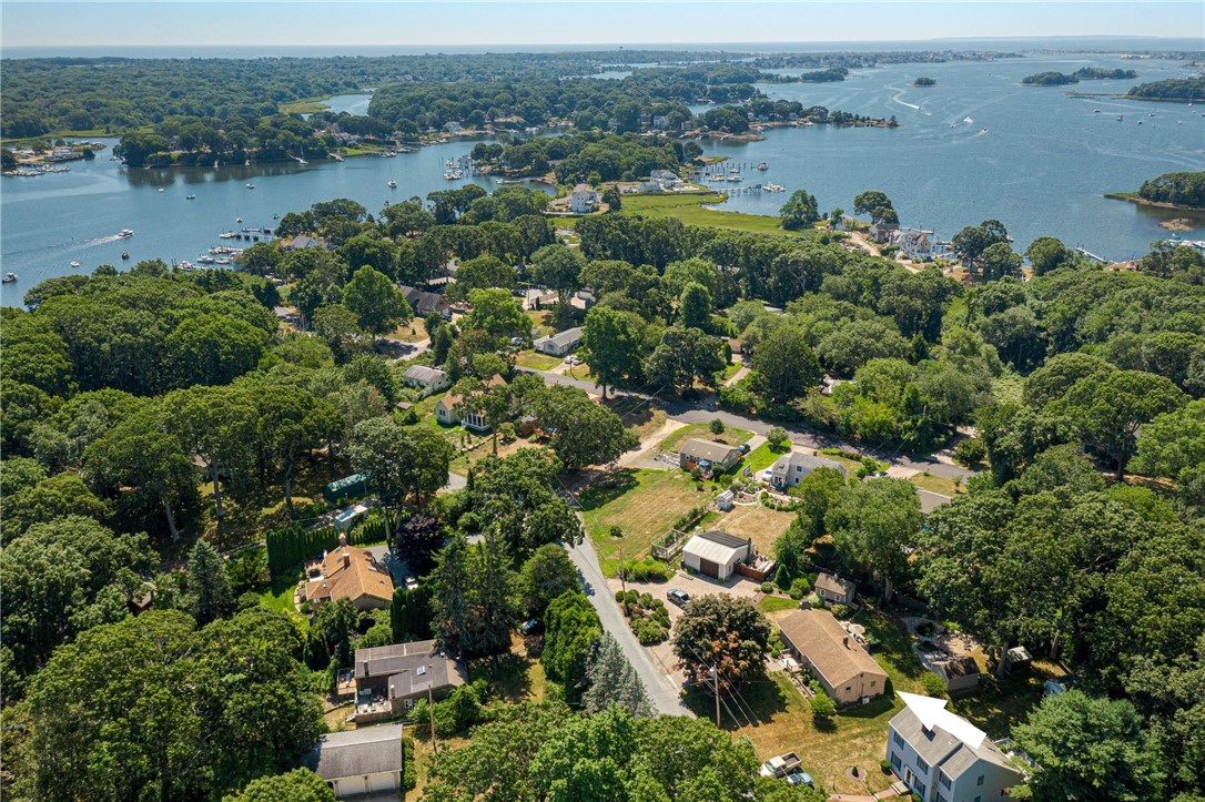 Aerial view of a wooded coastal neighborhood with homes, docks, and surrounding water.