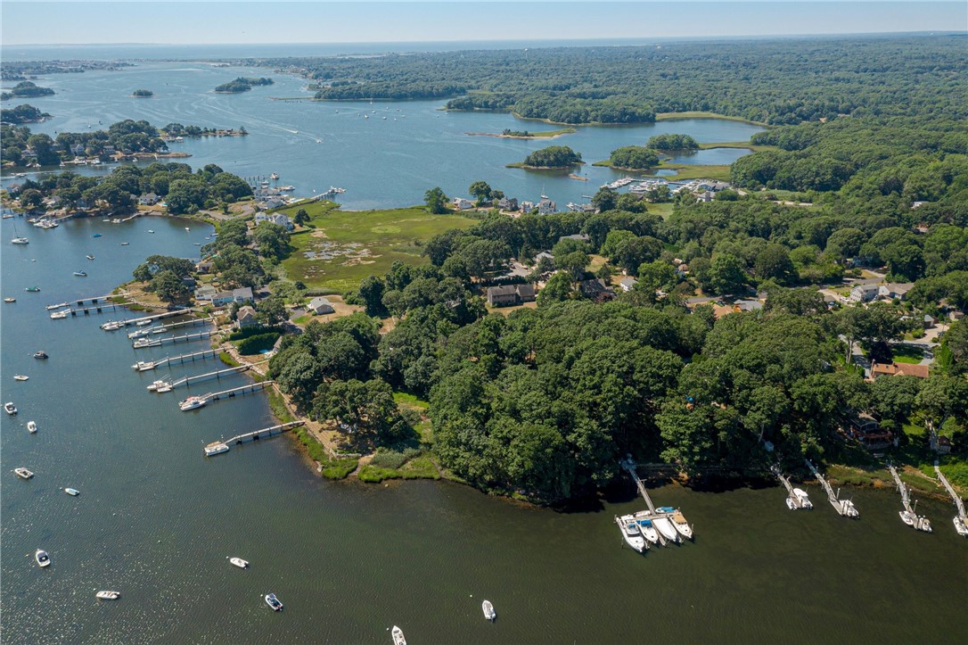 Aerial view of a wooded bayfront neighborhood with docks and boats along the shore.