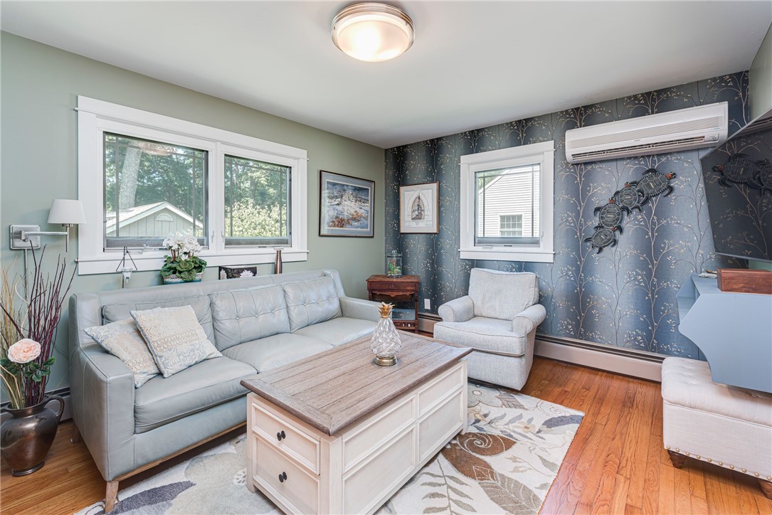 Living room with a pale blue sofa, patterned wallpaper, wood floors, and a white coffee table.