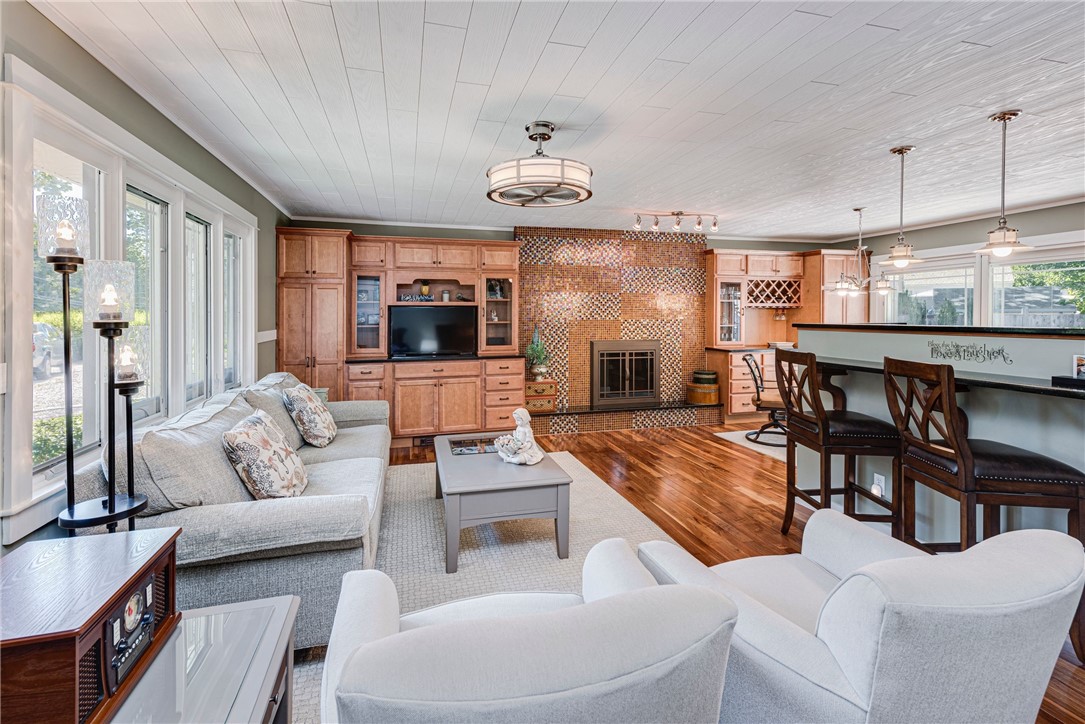 Living room with light sofas, a tiled fireplace, built-in wood cabinetry, and a breakfast bar.