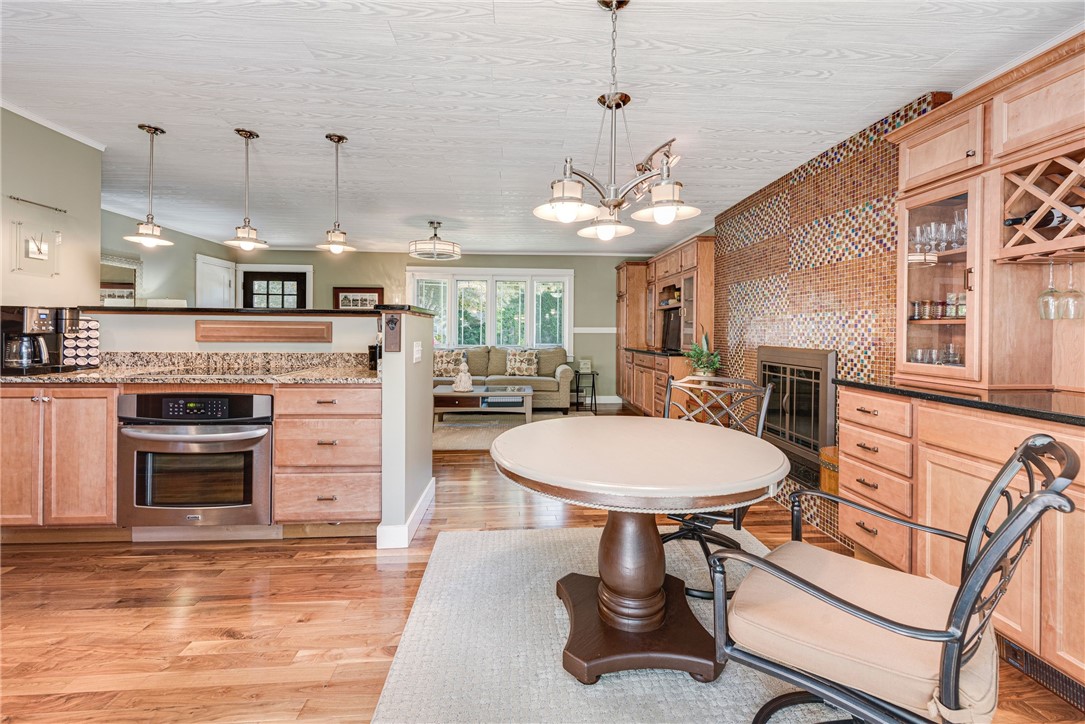 Open kitchen and dining area with wood cabinetry, mosaic tile wall, and round table.