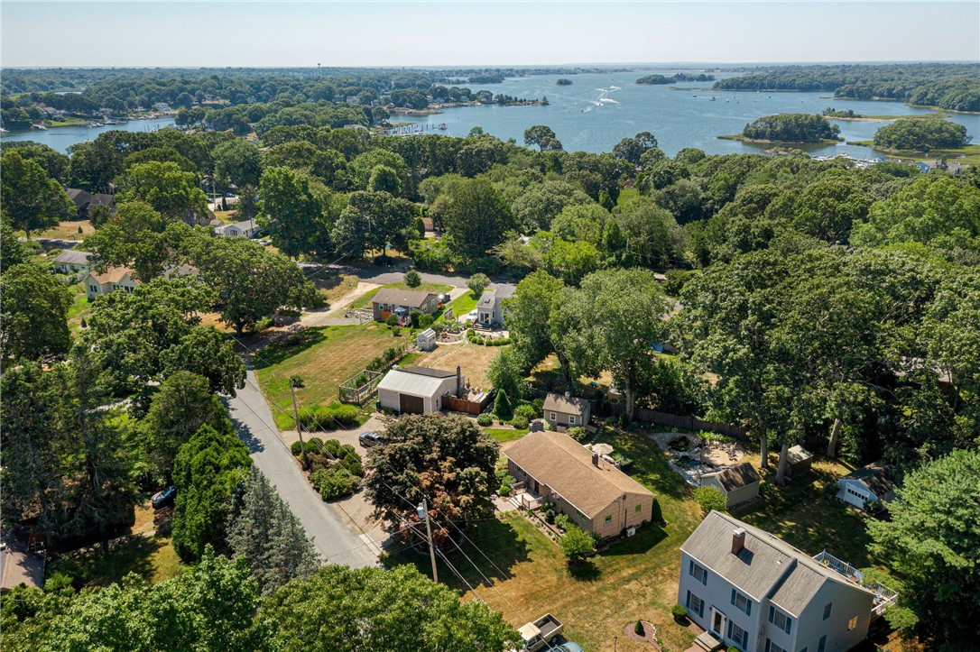 Aerial view of homes among trees beside a broad bay.