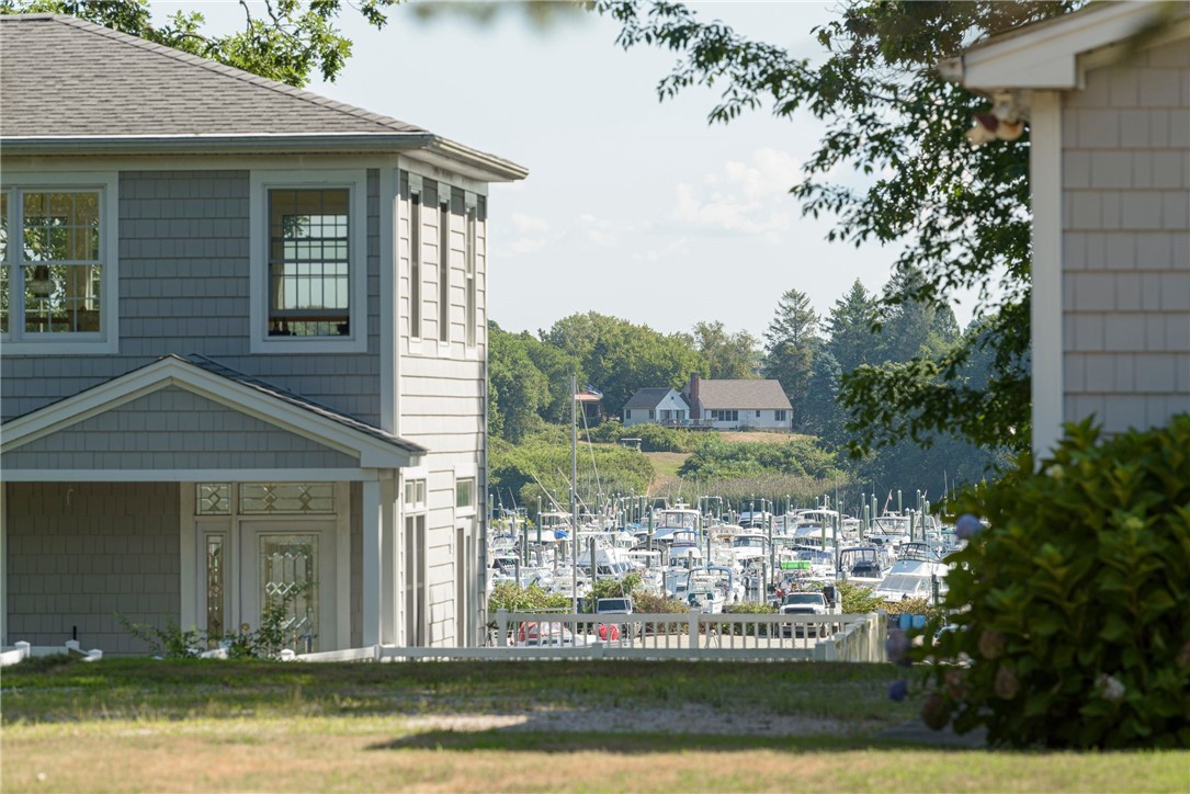 Gray shingle-sided home overlooking a marina filled with boats.