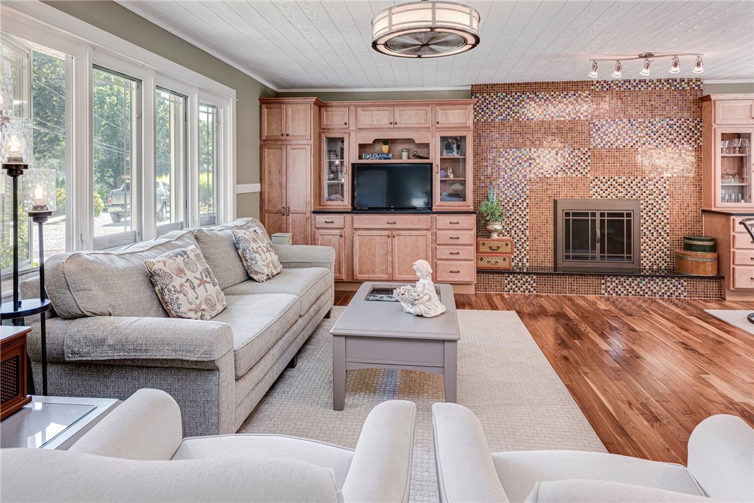 Living room with mosaic-tile fireplace, built-in wood cabinetry, and large windows.