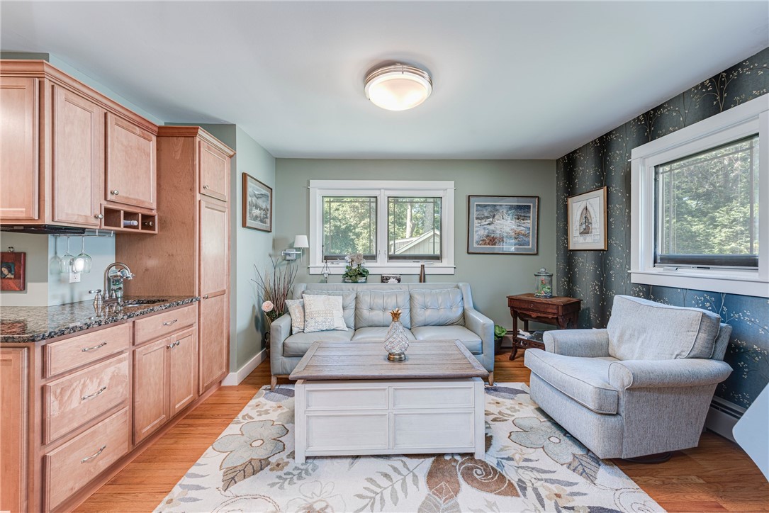 Living room with light blue sofas, pale wood cabinetry, floral rug, and dark botanical wallpaper.