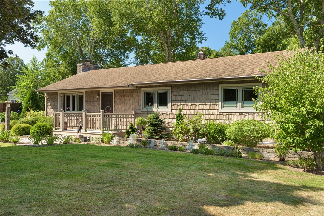 Single-story cedar-shingle home with a small front porch and landscaped garden beds.