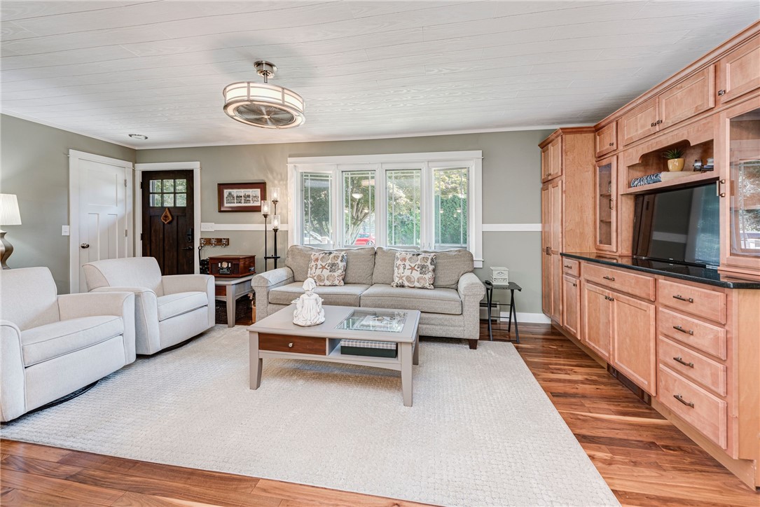 Living room with gray seating, hardwood floors, and built-in wood cabinetry around a television.