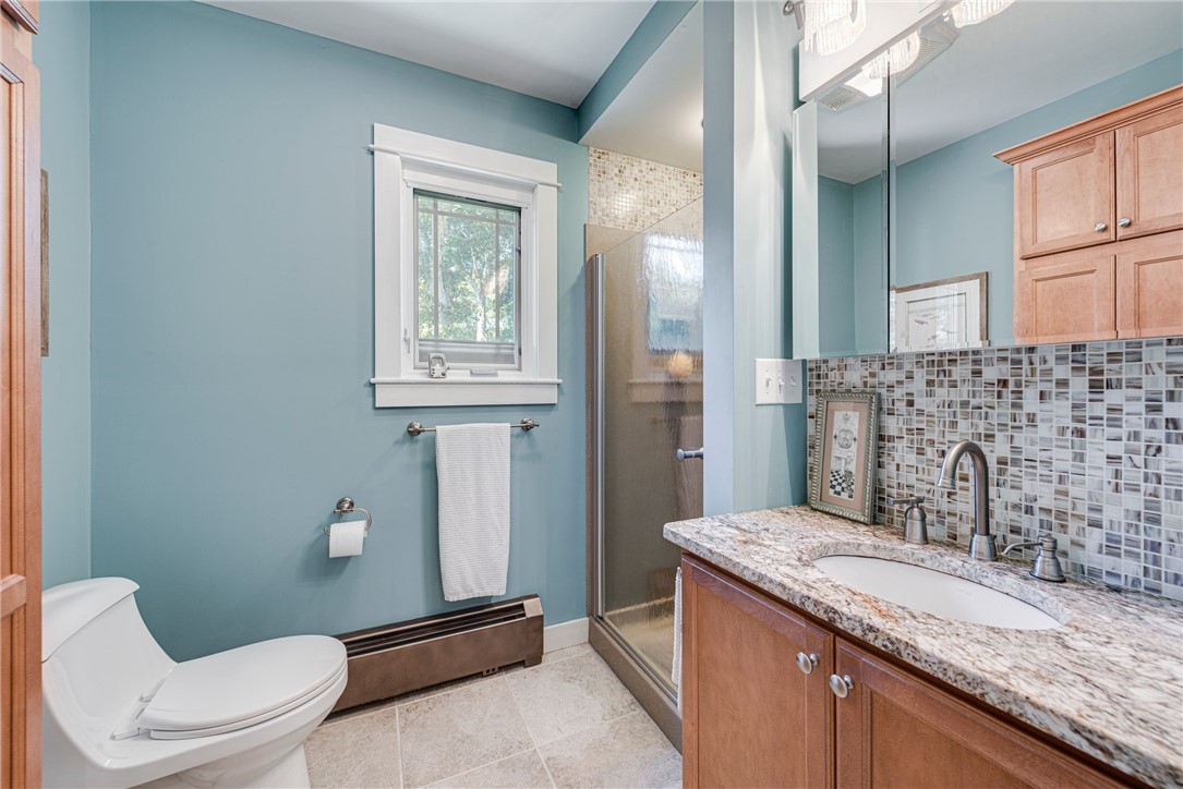 Bathroom with blue walls, a glass-enclosed shower, and a wood vanity beneath a tiled backsplash.