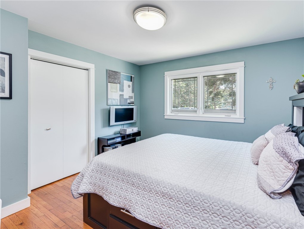 Bedroom with blue walls, a white quilted bed, and a double window overlooking trees.