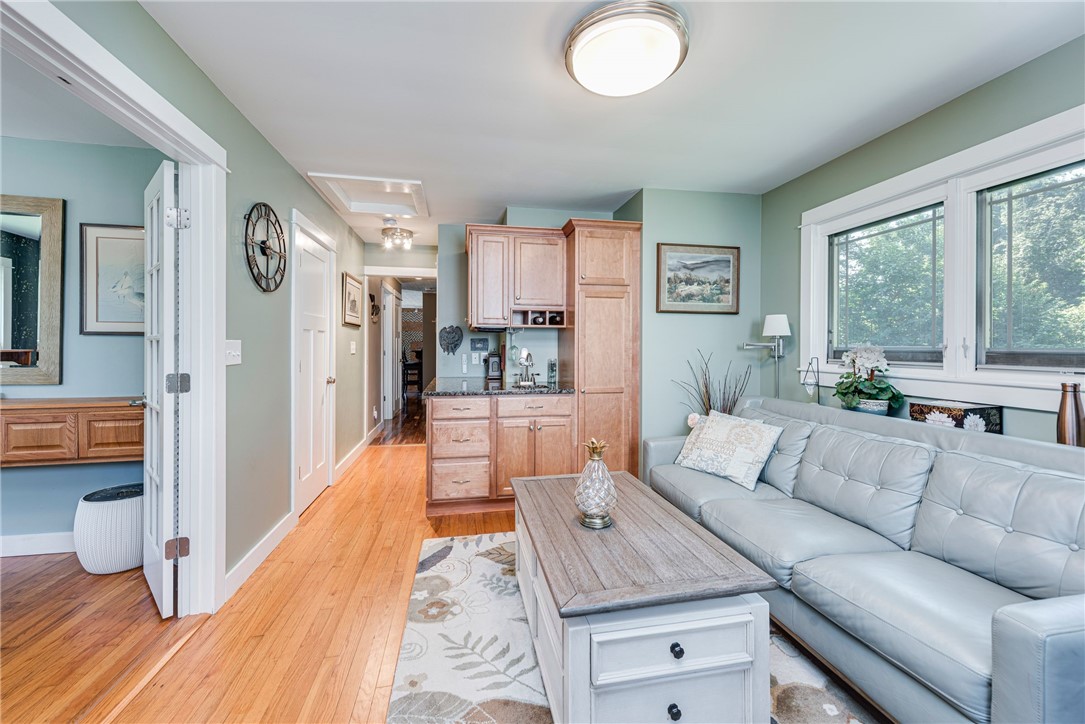 Living room with a gray sectional, wood coffee table, hardwood floors, and compact kitchen area.