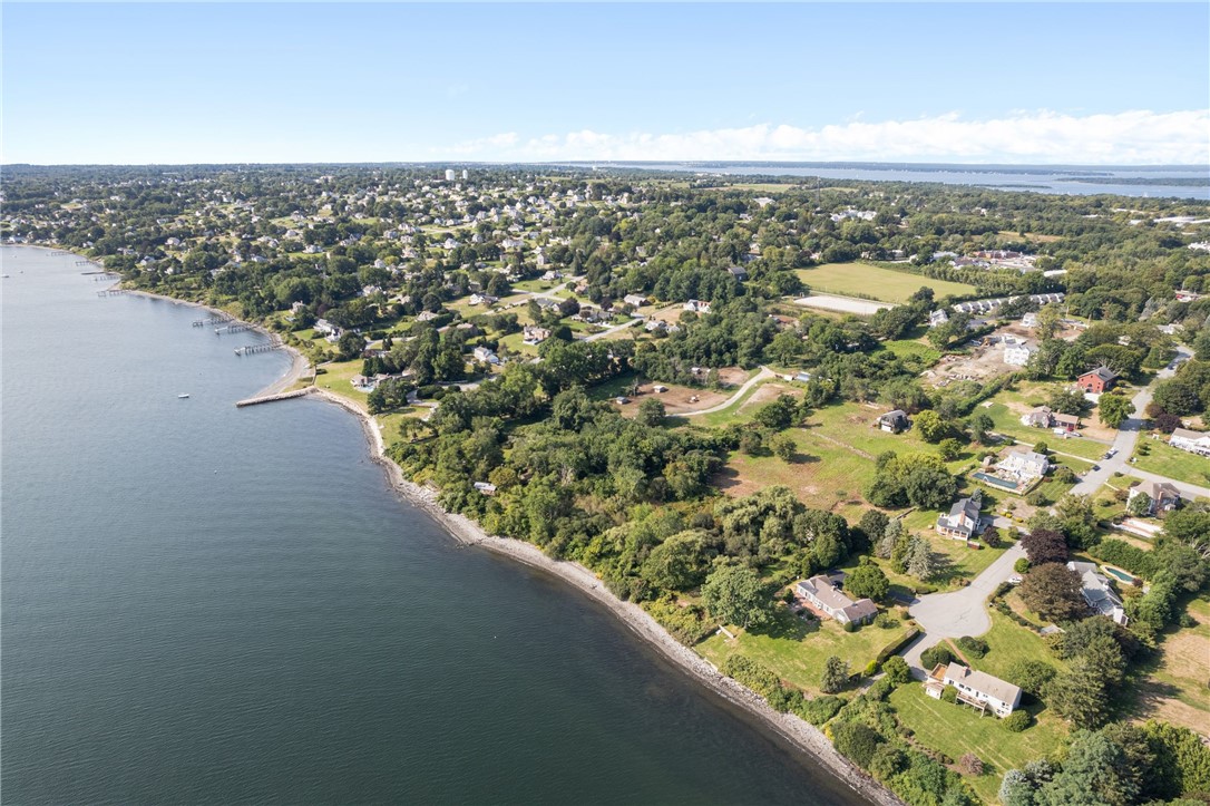 Aerial view of a shoreline neighborhood with waterfront homes, docks, and wooded lots.