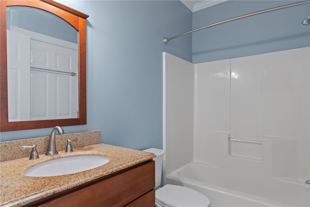 Bathroom with a granite vanity and white tub-shower combination.