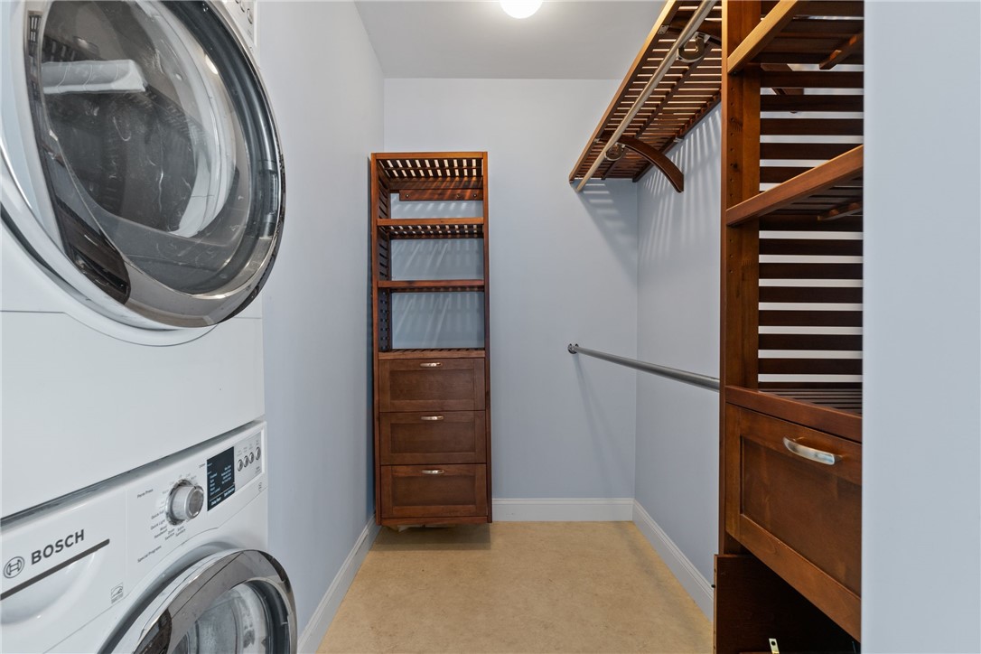 Laundry and walk-in closet with stacked Bosch machines and custom wood shelving.