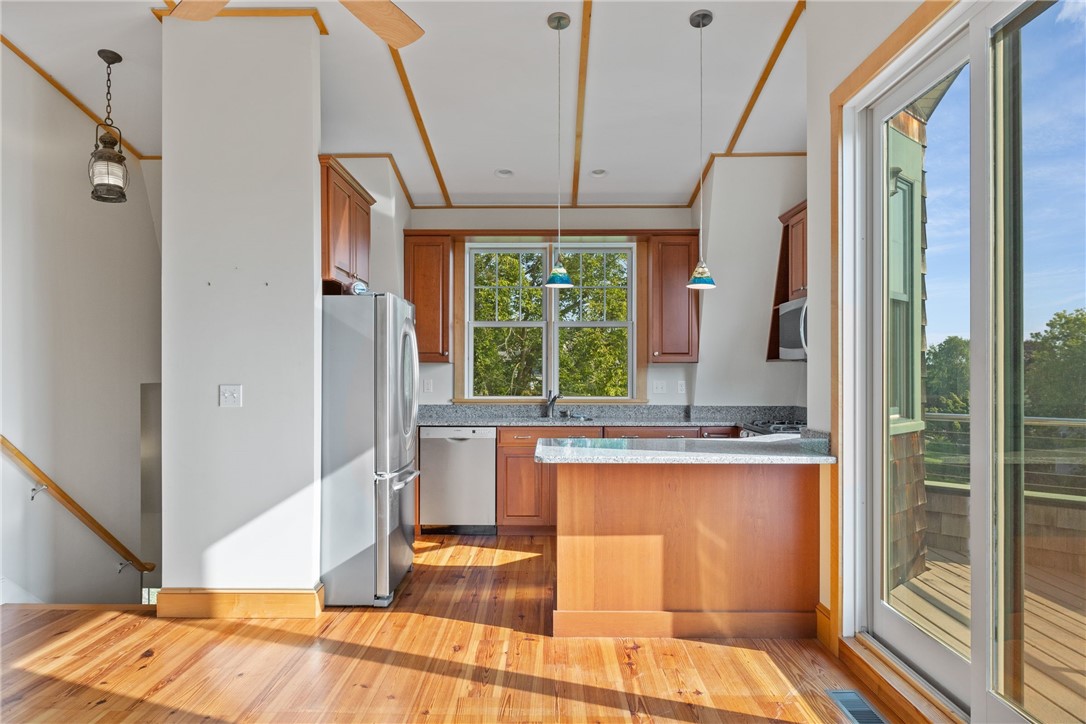 Kitchen with wood cabinetry, granite breakfast bar, hardwood floors, and sliding doors to a deck