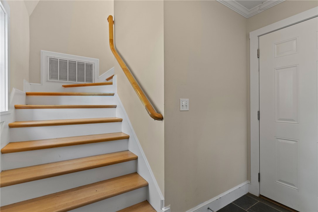 Entryway staircase with wood treads and handrails beside a white paneled door.