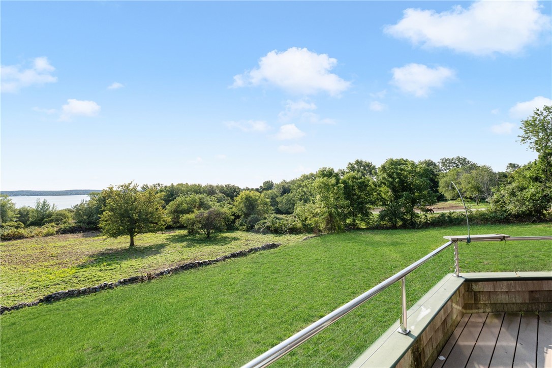 Green lawn and landscaped grounds with distant water, viewed from a deck.