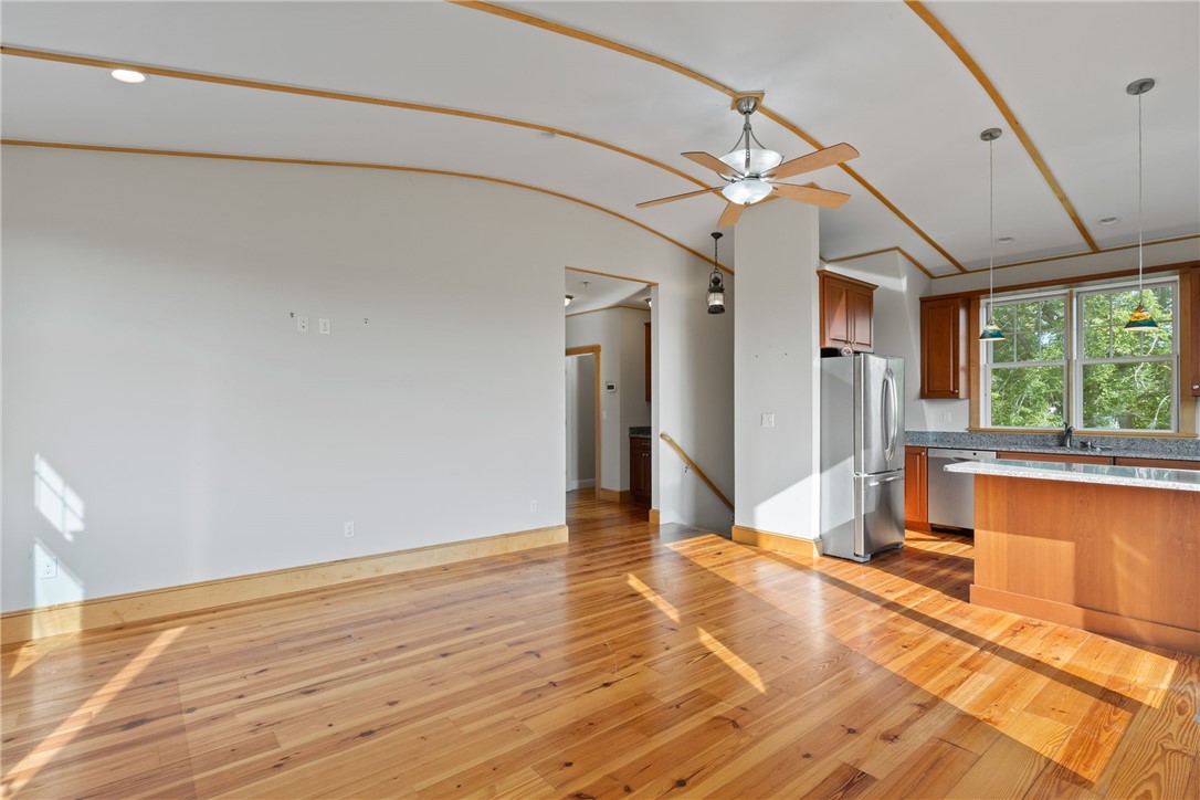 Open living and dining area with hardwood floors, curved ceiling trim, and an adjoining kitchen.
