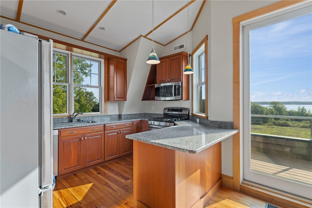 Kitchen with wood cabinets and granite peninsula beside a sliding door overlooking the water.