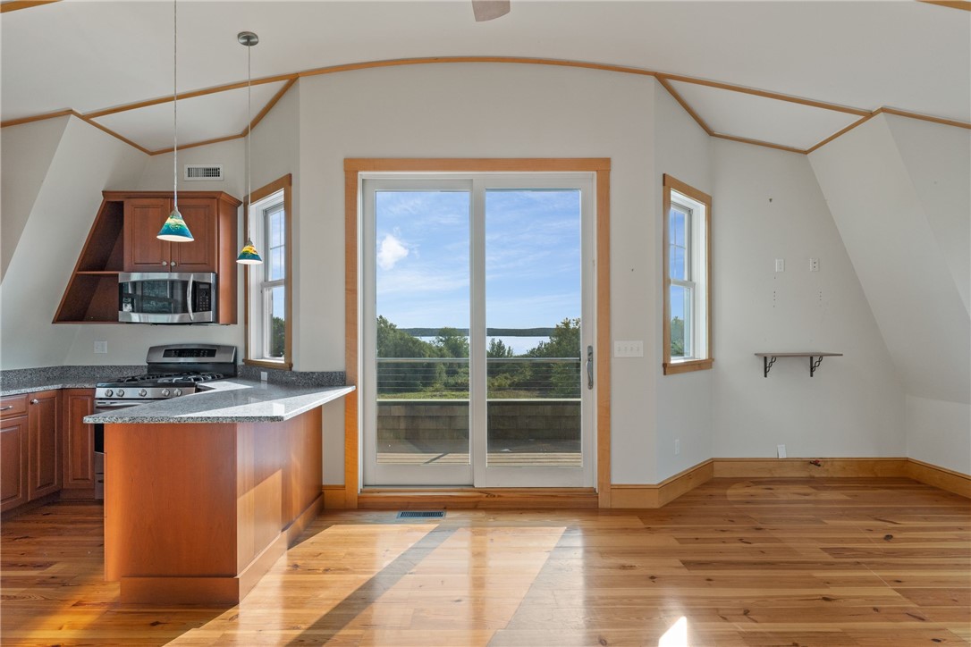 Kitchen with a granite island and hardwood floors, opening to a deck with a water view.