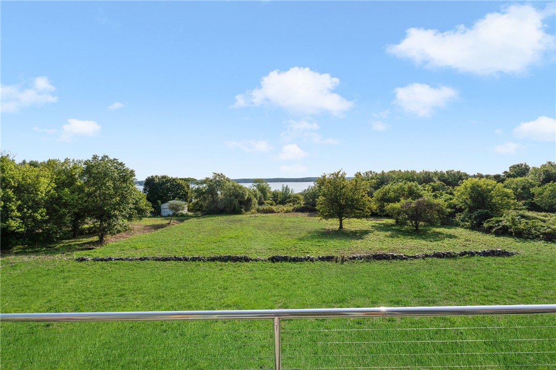Green lawn and stone wall with water visible beyond the trees.