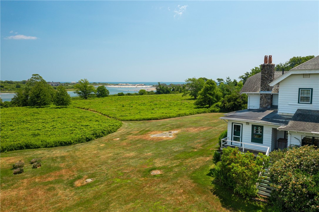 White coastal house beside a broad lawn, with marshland and water beyond.
