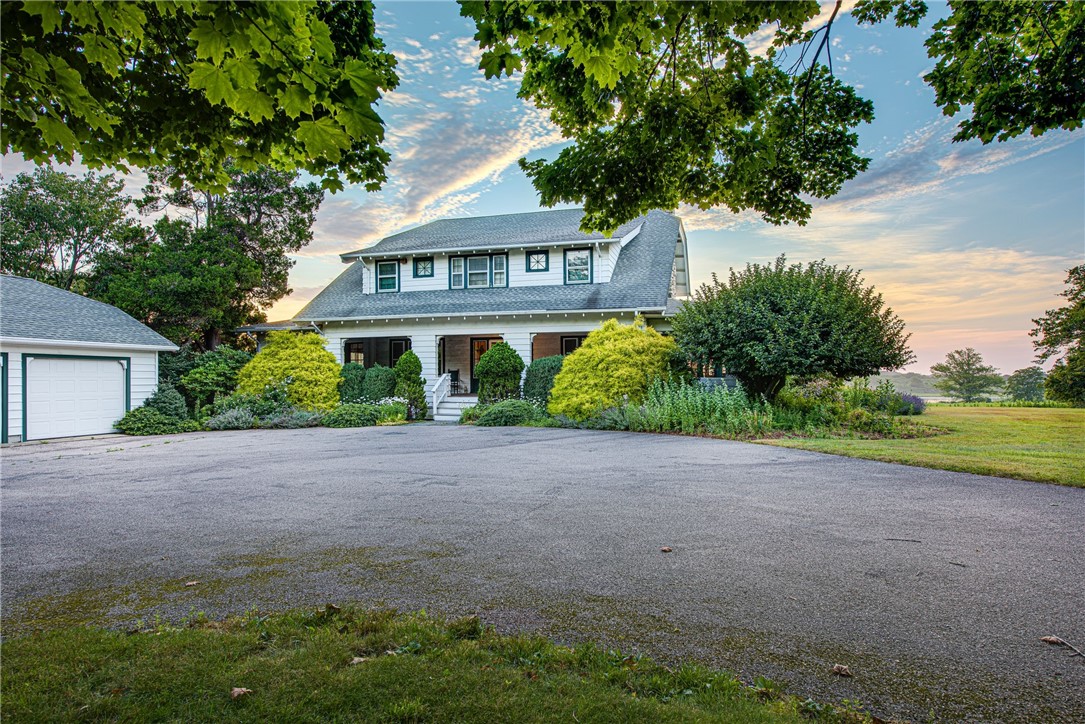 White two-story house with a detached garage, broad driveway, and landscaped front garden.